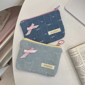 Dettaglio di portamonete in denim ricamato con fiocchi di raso rosa e cuori