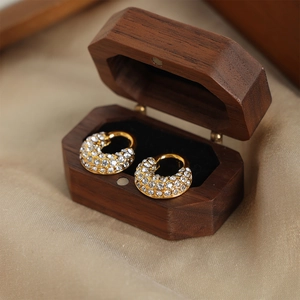 Élégantes boucles d'oreilles géométriques dorées avec diamants dans un coffret en bois
