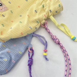 Detail of drawstring pouches with colorful polka dots, plaid fabric, and beaded rope accents