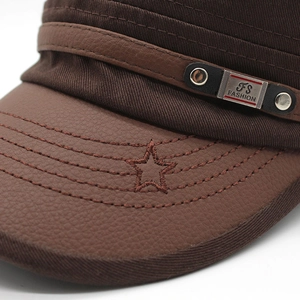 Detail of dark brown flat cap showing leather texture, star embroidery and metal plaque