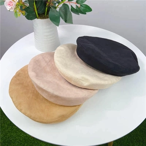 Detail of soft suede beret hats in black, cream, pink and khaki on a white table