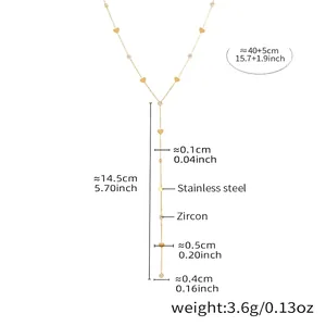 Détail d'un collier en Y doré avec breloques cœur et zircon sur fond blanc pur