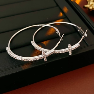 Dettaglio orecchini a cerchio in argento con cristalli scintillanti e design a croce