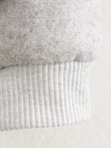 Vue détaillée des poignets en maille côtelée gris clair et de la texture polaire
