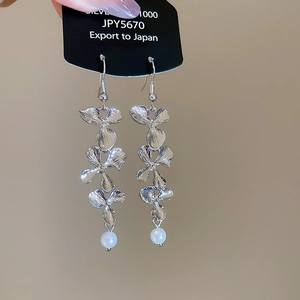 Close-up of layered silver flower earrings featuring a pearl drop and S1000 metal shine