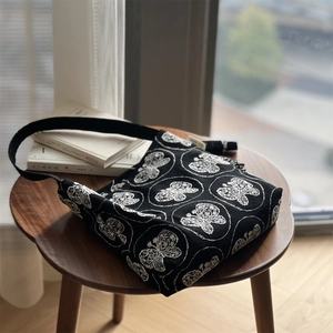 Detail der weißen Schmetterlingsstickerei auf schwarzer Canvas-Tasche mit Premium-Textur