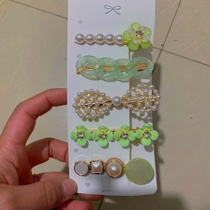 Detail view of 5-piece hair clip set with green resin, faux pearls, and floral motifs