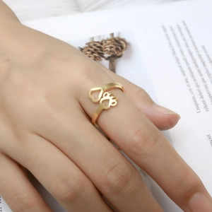 Detail of adjustable gold ring with hollow heart and paw print patterns on female hand