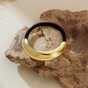 Elastic ponytail holder with gold moon metal ornament on a natural rock texture