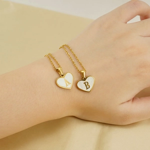 Macro shot of gold heart necklace with white shell inlay featuring letters A and B