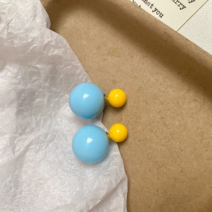 Close-up of light blue and yellow double bead resin stud earrings in a craft box