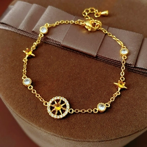 Detail of gold zircon star compass bracelet with 18K gold texture on velvet display