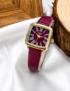Gros plan d'une montre carrée dorée avec bracelet en cuir bordeaux et chiffres romains