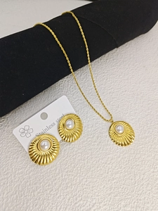 Detail of gold stainless steel necklace and earrings set with pearls on a black display stand