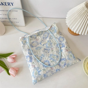 Detail of light blue floral lace tote bag with delicate white embroidery and brand patch