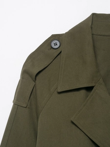 Close-up of military green trench coat featuring twill fabric and epaulet with black button
