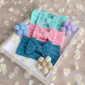 Three colorful nylon baby headbands with textured bows on daisy tulle background