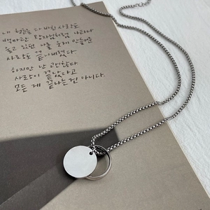 Minimalist silver hip-hop necklace with geometric disc pendant on a book background