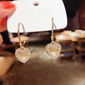 Détail de boucles d'oreilles cœur dorées avec tiges en argent S925 et cristaux brillants