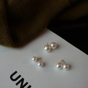 Detailed close-up of three pairs of elegant white pearl stud earrings with gold posts