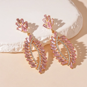 Detailed close-up of golden geometric leaf tassel earrings with pink crystals and rhinestones