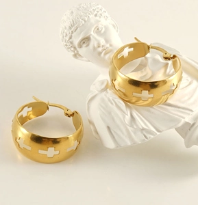 Detail view of gold wide hoop earrings featuring hollow cross patterns on the surface