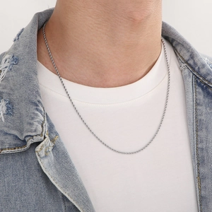 Close-up of a silver stainless steel rope chain necklace on a model wearing casual clothes