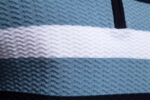 Macro shot of 3D textured wavy knit fabric with light blue and navy horizontal stripes
