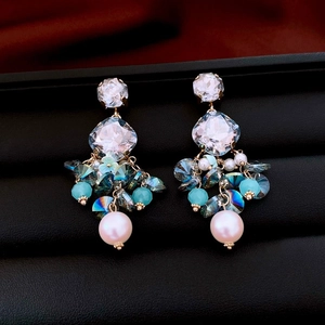 Detail of luxury heart fringe earrings with blue crystals and pearl pendants