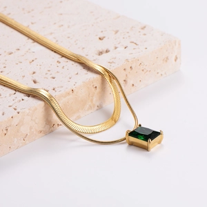 Elegant gold snake chain necklace with a square green zircon pendant on stone