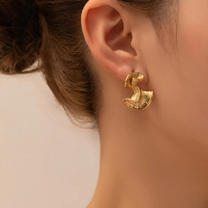 Close-up of golden abstract petal earrings with textured hammer finish on a model