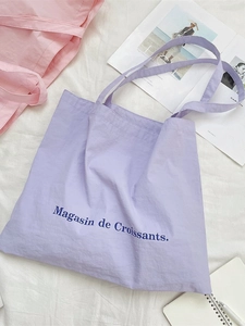 Minimalist purple canvas tote bag with French croissant text and stationary aesthetic