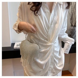 Detailed view of silver heart-shaped clutch with shimmering rhinestones and long tassels