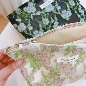 Macro detail of floral embroidery on mesh pouches with zipper and simple wish label