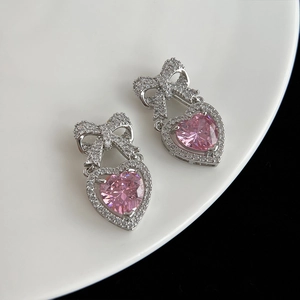 Détail macro de boucles d'oreilles nœud en argent avec zircon cœur rose et cristaux