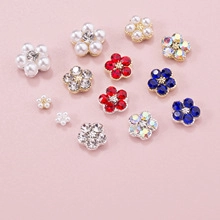 Flat lay of colorful DIY flower charms with rhinestones and pearls on pink background