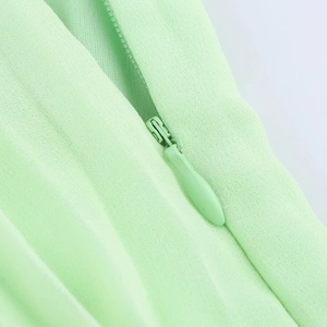 Detail of high-quality invisible zipper on mint green pleated skirt with textured fabric