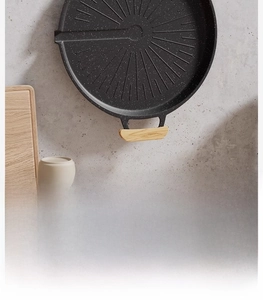Detail of round non-stick grill pan with medical stone coating and wooden handles