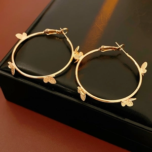 Détail de boucles d'oreilles créoles papillon dorées sur boîte à bijoux noire