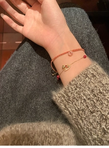 Close-up of double-layer 18k gold plated bracelets with red beads on a female wrist