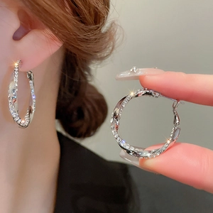 Detail of silver hoop earrings with twisted geometric design and crystal embellishments