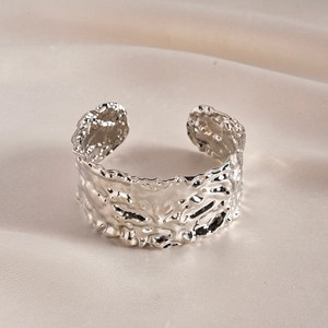 Detailed shot of silver liquid metal texture bangle on a luxury champagne silk background