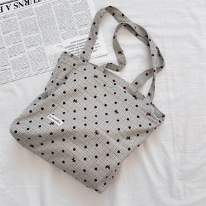 Detailed view of canvas tote bag with vichy plaid pattern and red polka dots on white cloth