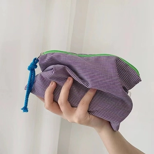 Detail of purple gingham cosmetic bag with vibrant green zipper and blue pull cord