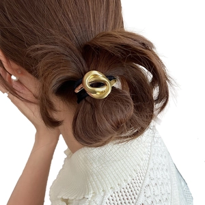 Detailed view of a golden metal double-ring hair tie worn on a ponytail