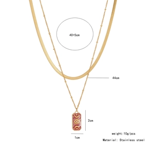 Detail of gold double layer necklace with red enamel sun and moon pendant in stainless steel