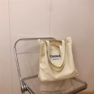 Détail d'un grand sac cabas en toile épaisse avec écusson CHINA et BOUNCE BACK sur tissu crème