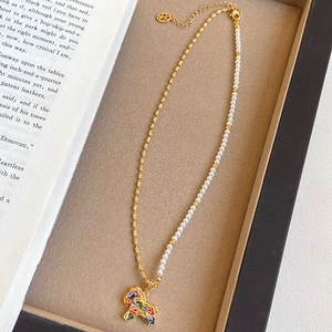 Detail der Pferde-Halskette mit Goldkette und weißen Perlen auf einer beigen Box