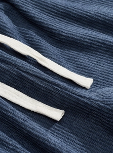 Detail shot of blue corduroy fabric texture and white braided drawstrings on sports jacket