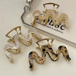 Three acetate wave hair claws in beige, marble, and leopard print with gold metal base